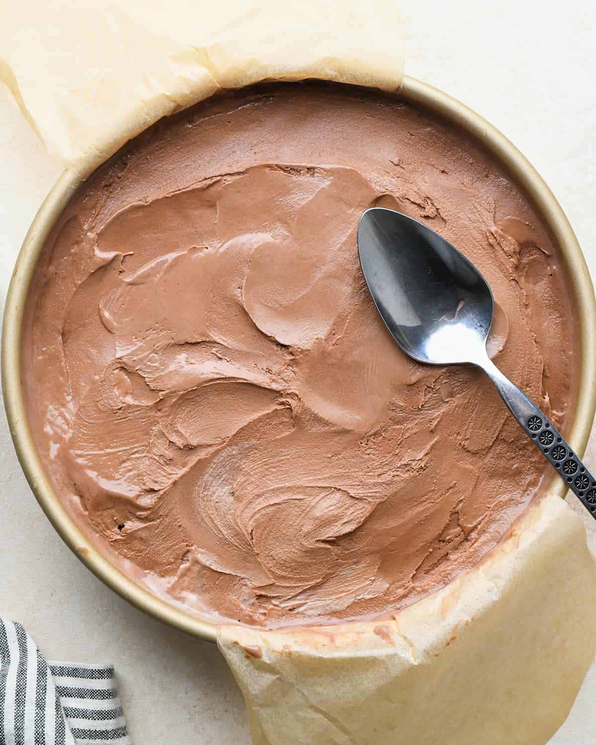 assembling an ice cream cake - ice cream on top of the fudge layer in a cake pan after spreading out