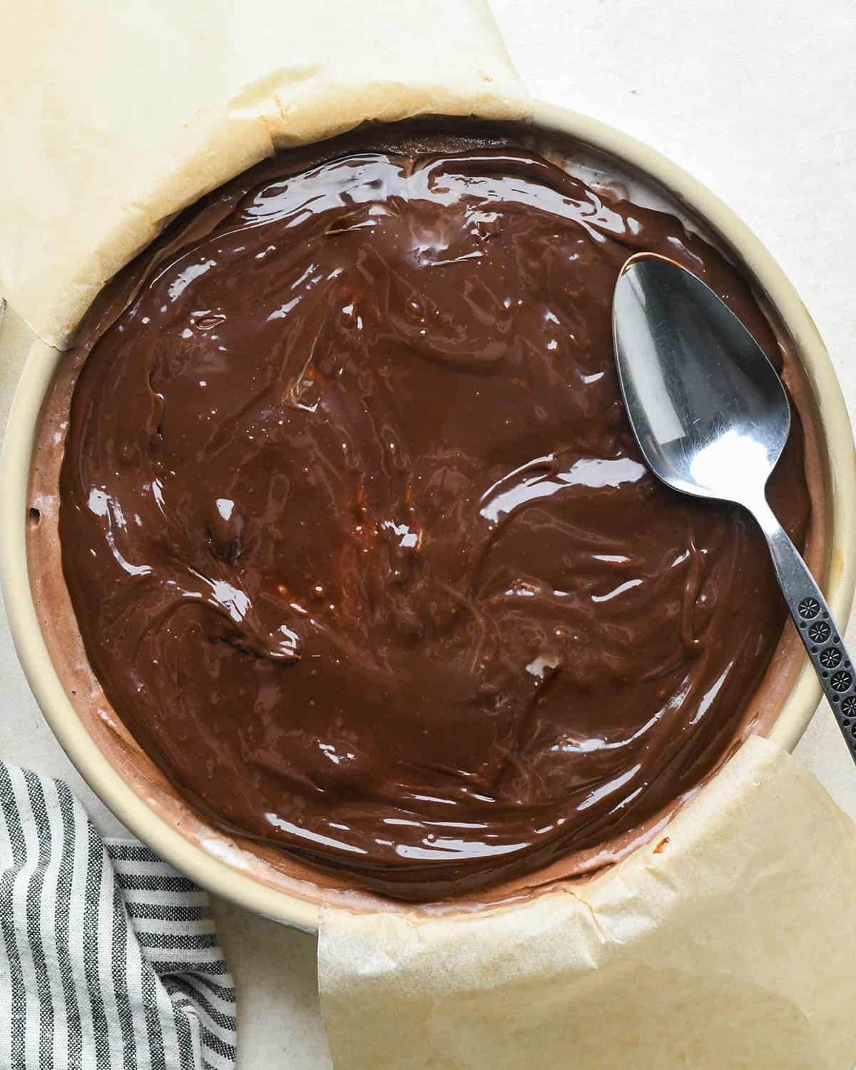 assembling an ice cream cake - fudge sauce on top of the chocolate ice cream layer in a cake pan after spreading out