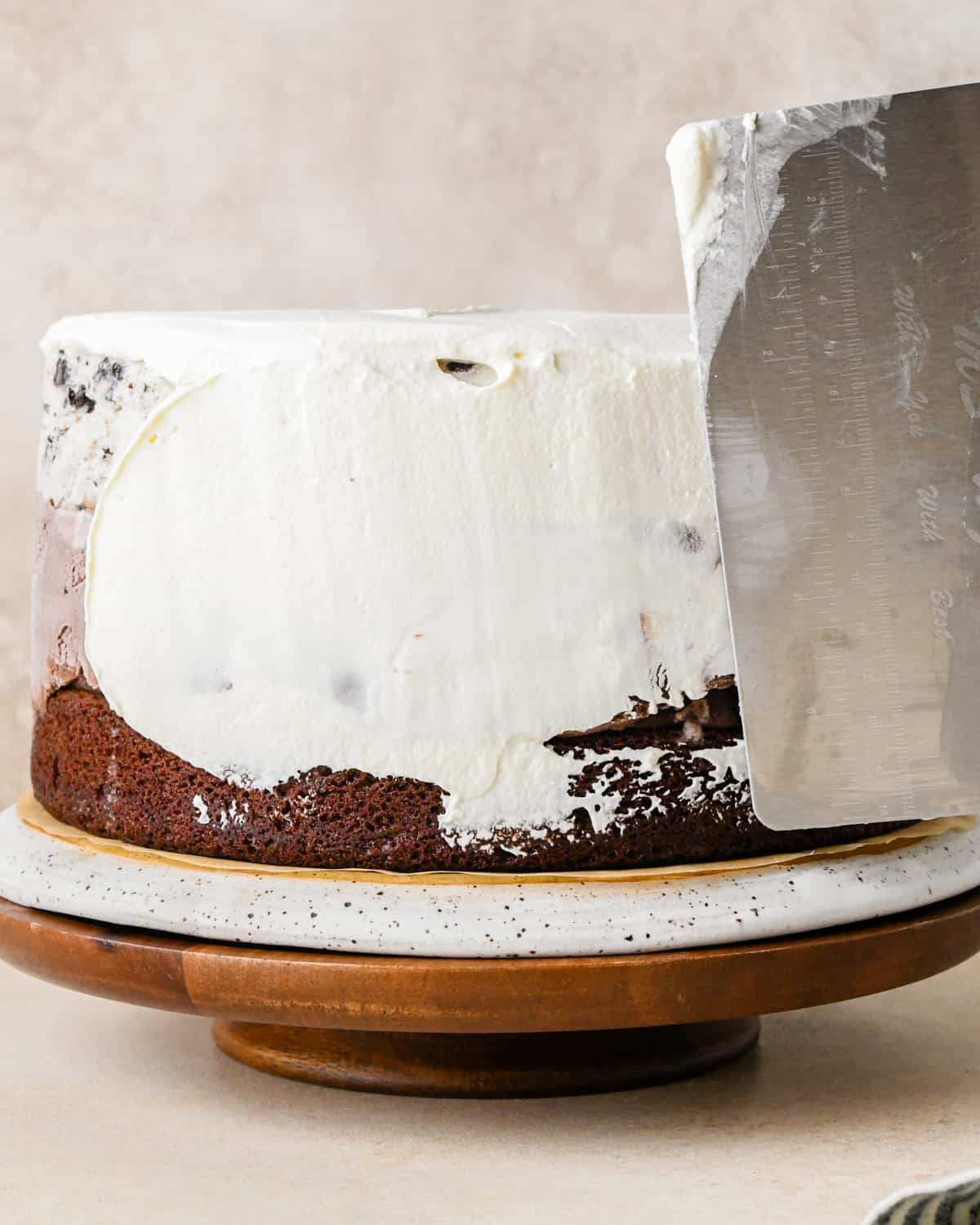 whipped cream being spread over an ice cream cake as frosting