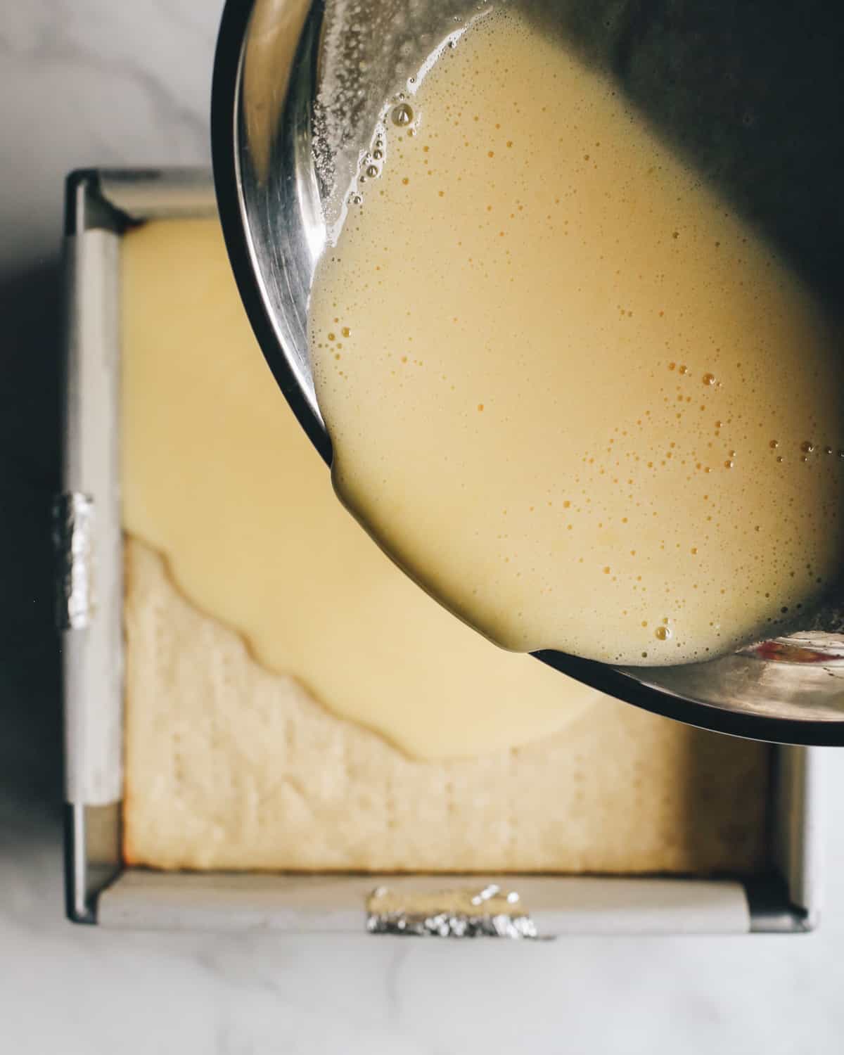 How to Make Lemon Bars - lemon filling being poured into the partially baked crust