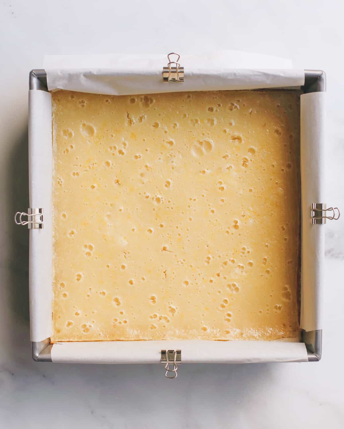 The best lemon bars! A smooth & sweet lemon filling sits on top of a buttery shortbread crust for the most delicious lemon squares recipe. Plus these easy lemon bars are simple to make with only 8 ingredients! lemon bars after baking in a baking dish