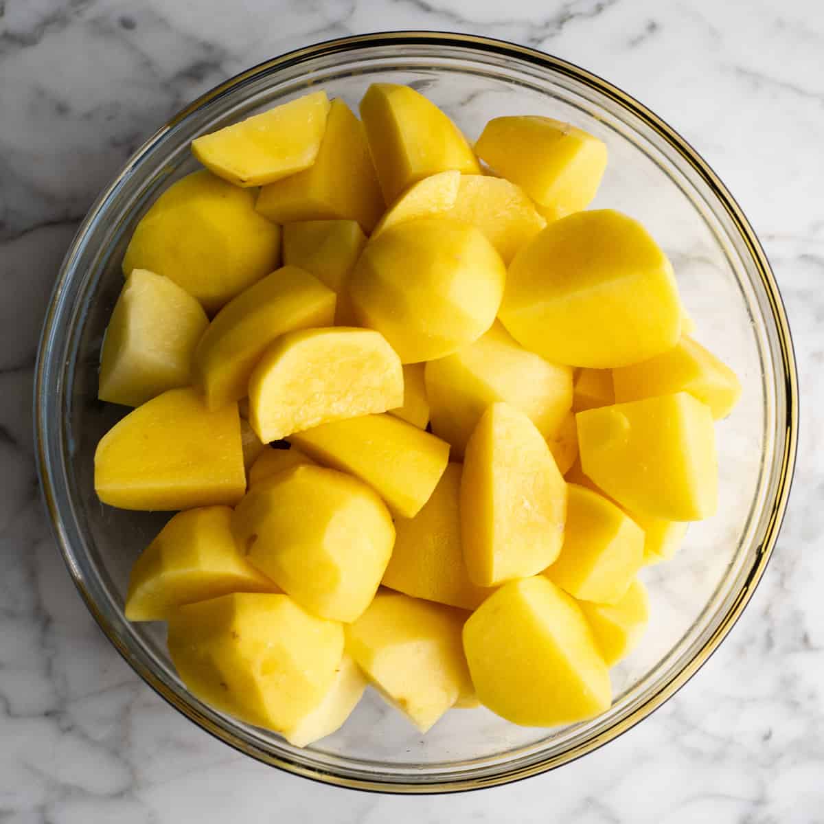 These herb-infused garlic mashed potatoes are the best mashed potatoes you will ever eat. They are creamy, fluffy buttery and so insanely delicious you will never make another mashed potatoes recipe again. Plus they're easy to make and can be prepared ahead of time! overhead photo of cut and peeled mashed potatoes