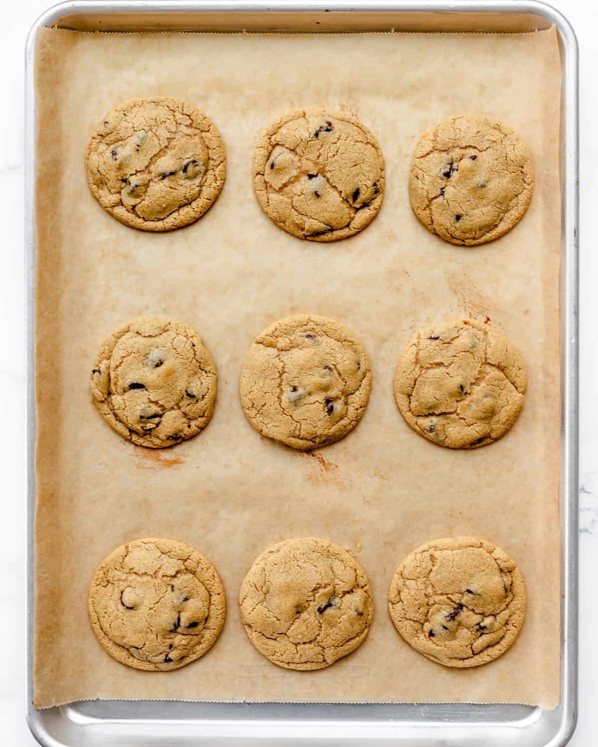 9 oat flour chocolate chip cookies on a baking sheet after baking