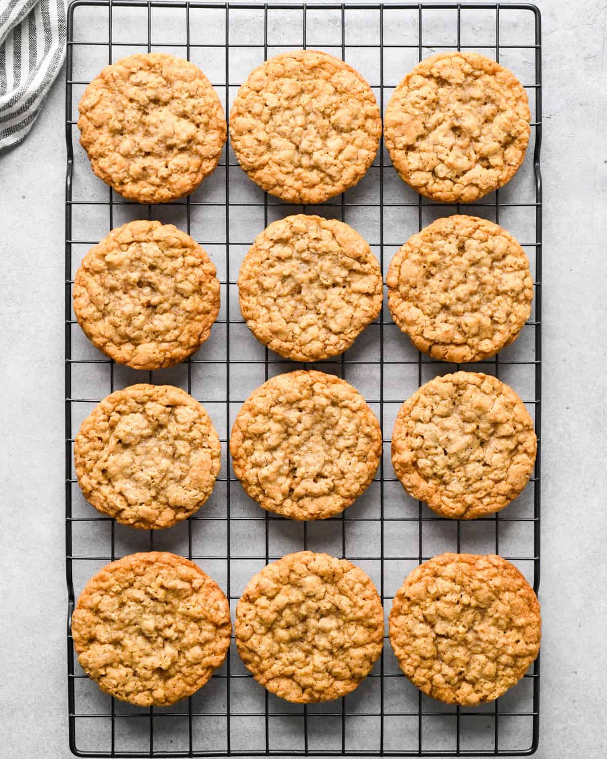 The BEST Oatmeal Cookie Recipe - crispy edges with soft and chewy centers, these oatmeal cookies are easy to make and out-of-this-world delicious. Add your favorite mix-ins for an extra special twist! #oatmealcookies #cookies #baking 12 oatmeal cookies on a wire cooling rack