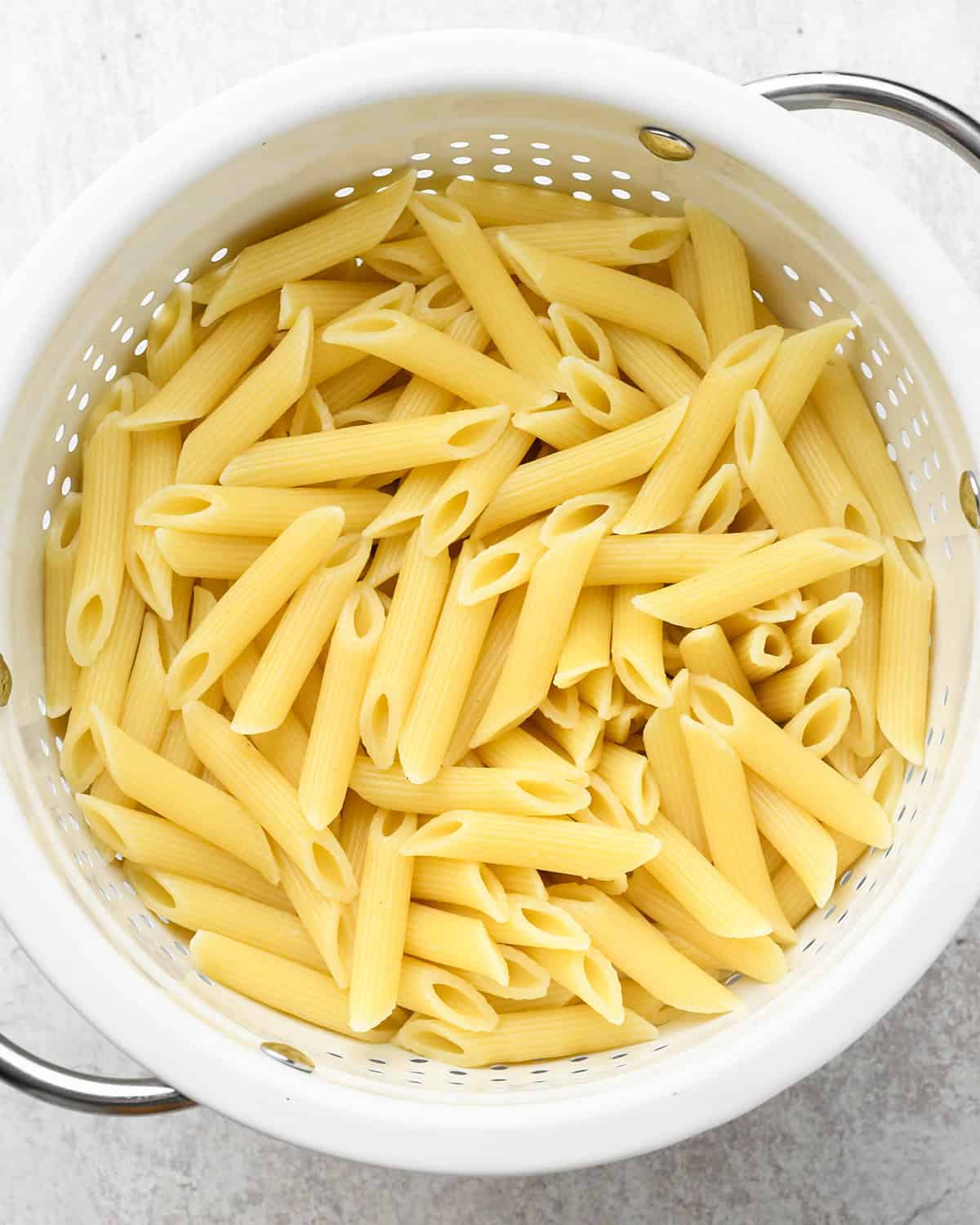 penne pasta draining in a colander to make pasta salad