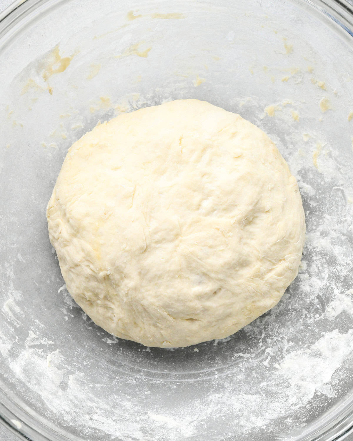 pizza dough in a glass bowl on a gray surface
