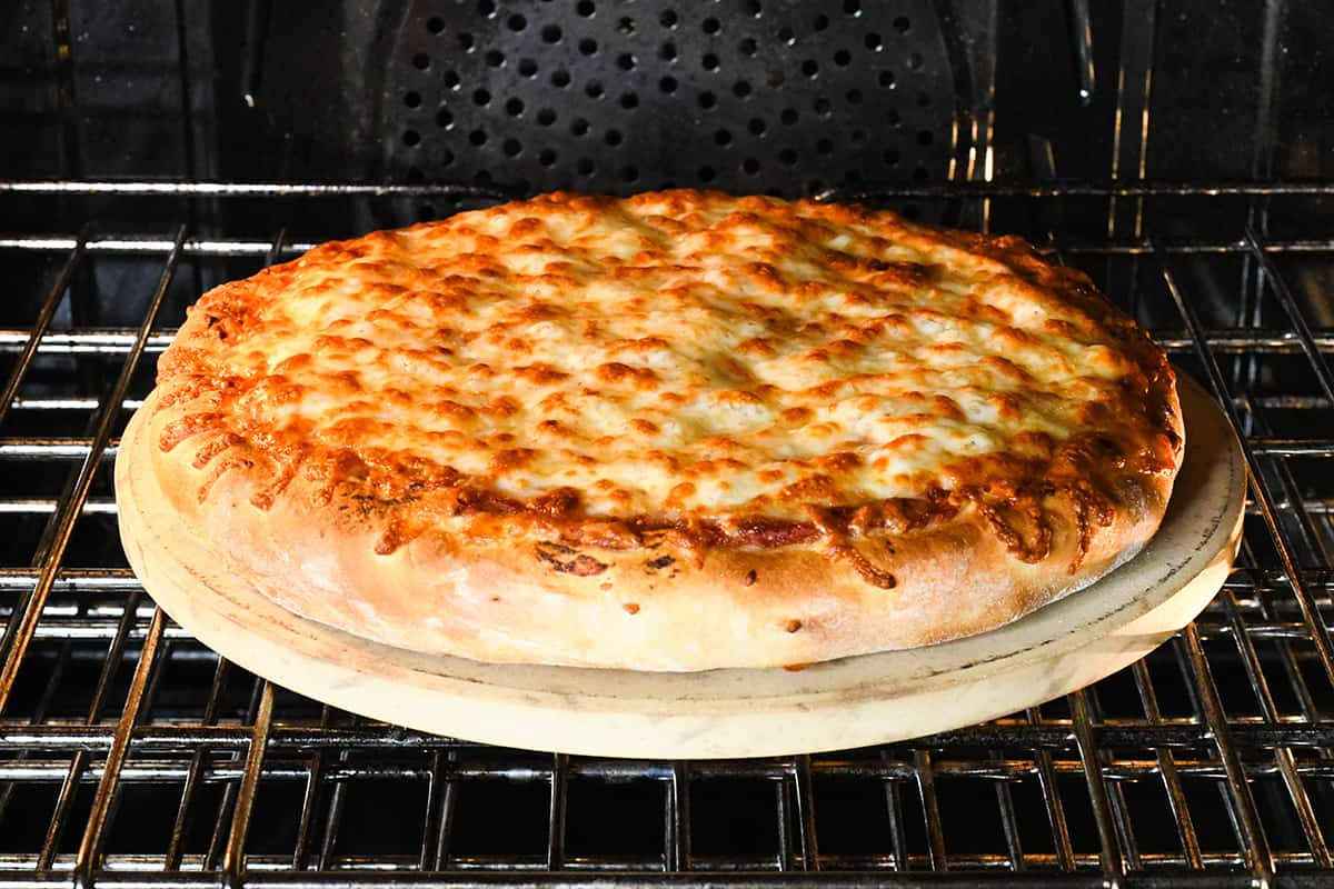 homemade pizza finished baking on a pizza stone int he oven