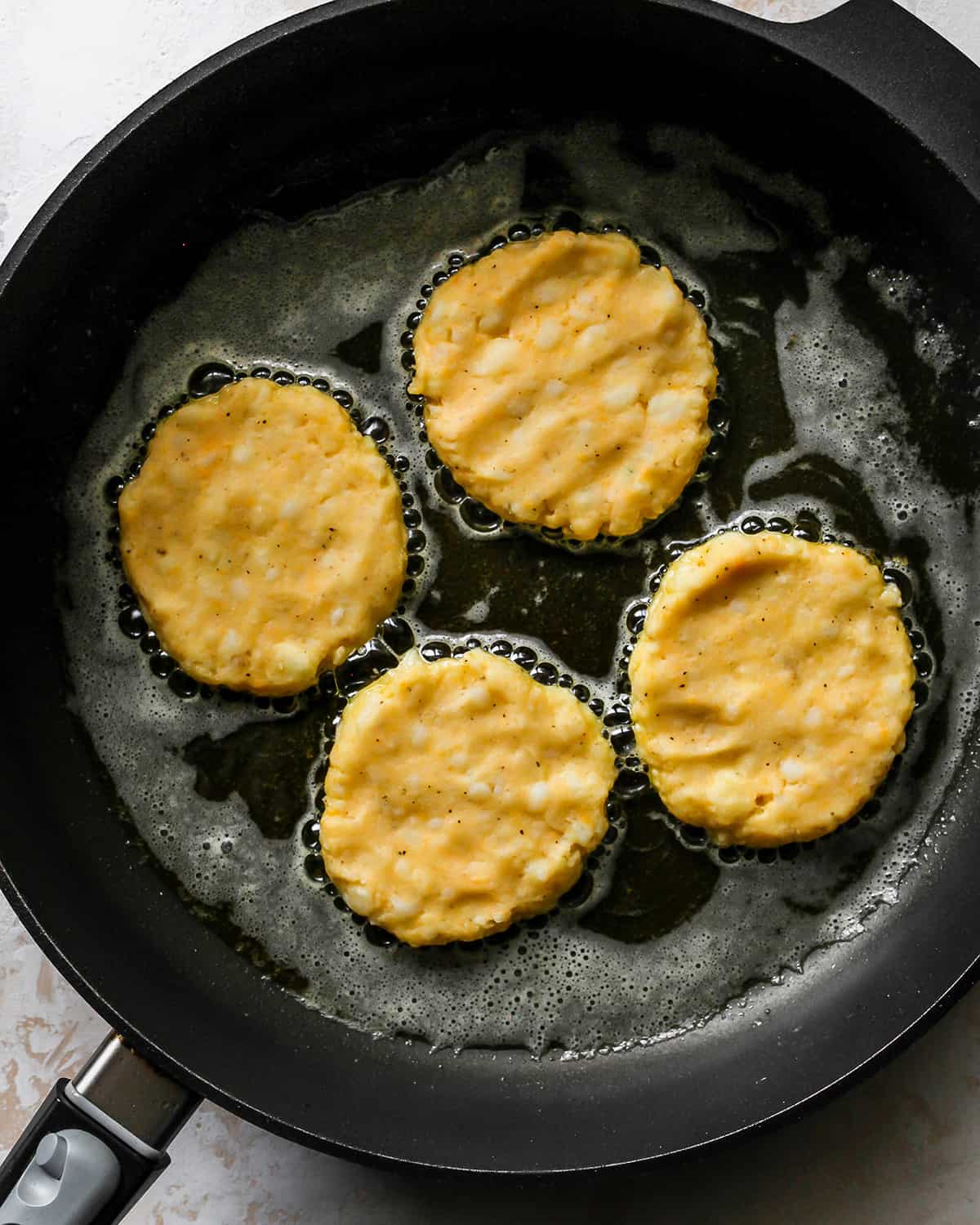 How To Make Potato Pancakes - cooking potato pancakes on the first side in an oiled skillet