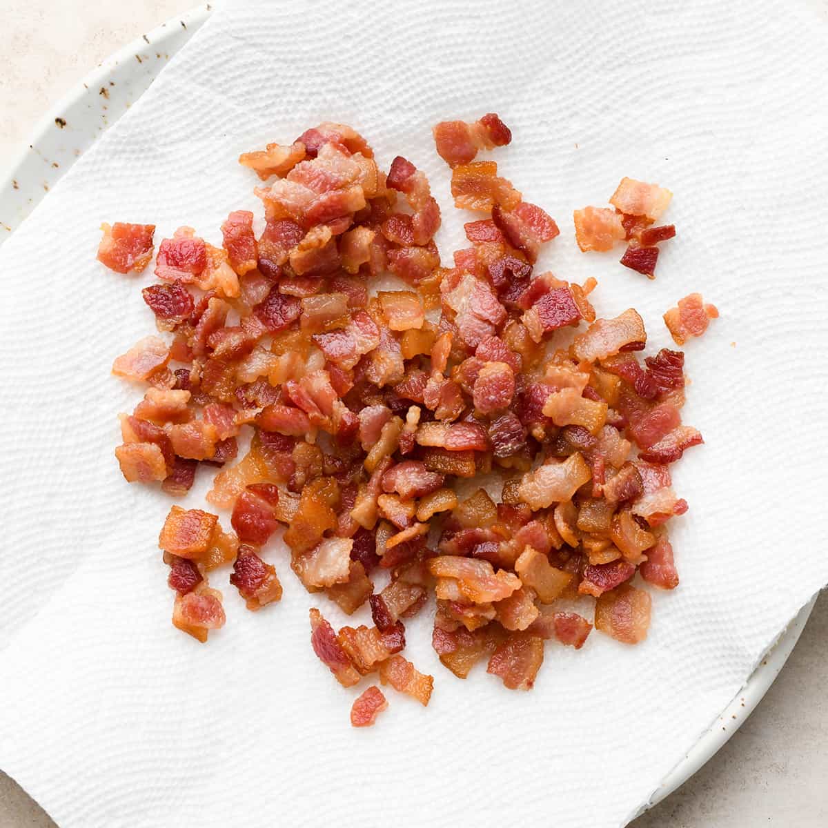 diced and cooked bacon on a plate lined with a paper towel to use in this potato soup recipe