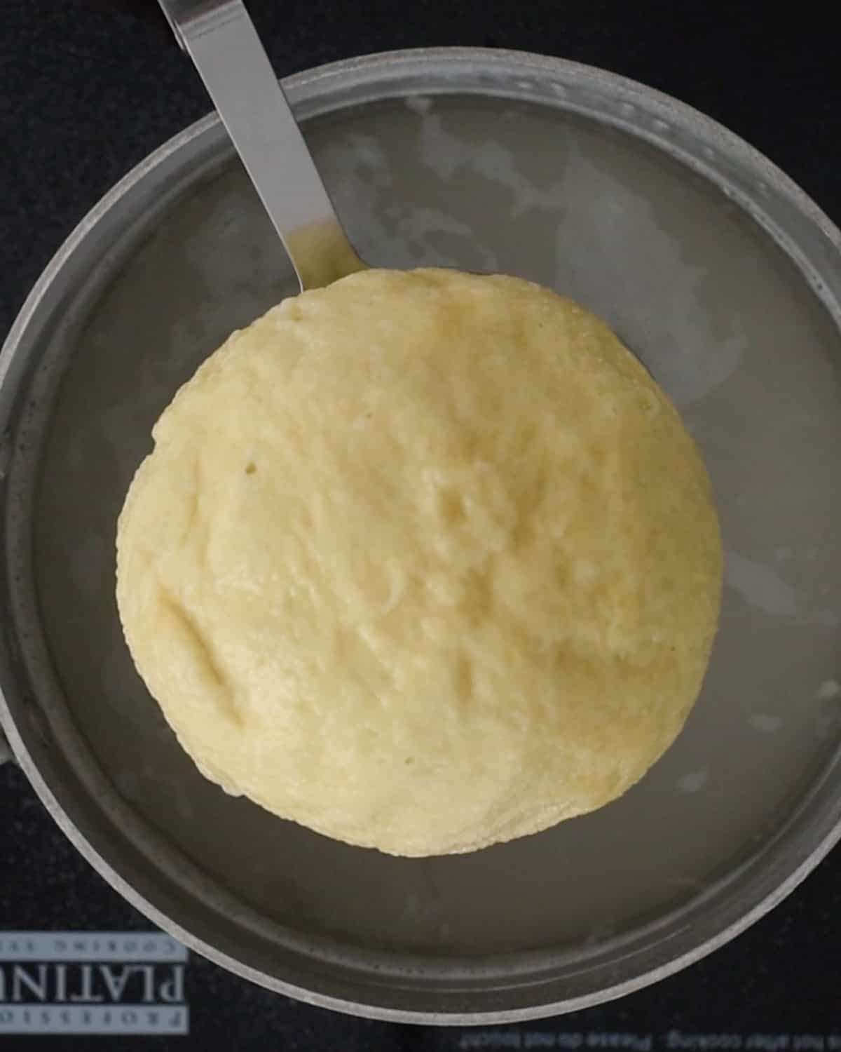 How to Make Pretzel Bread - dough being removed from a baking soda water bath