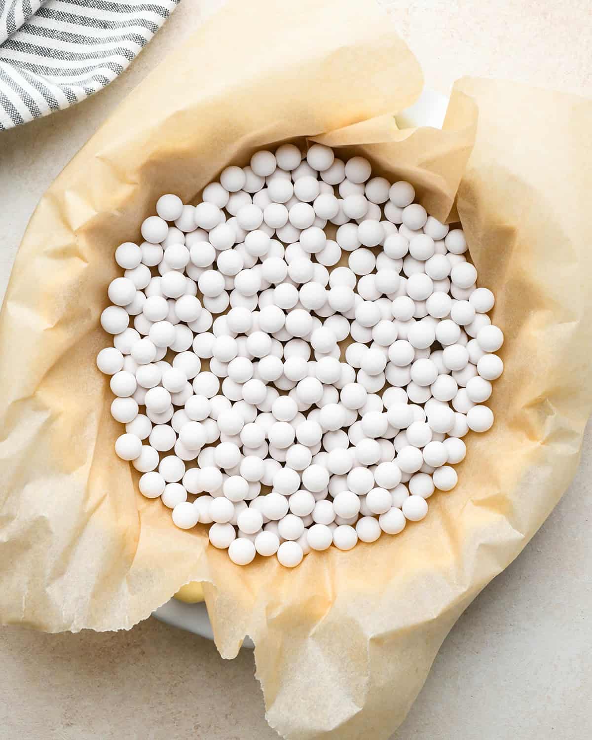 unbaked quiche crust in a pie dish with parchment paper and weights