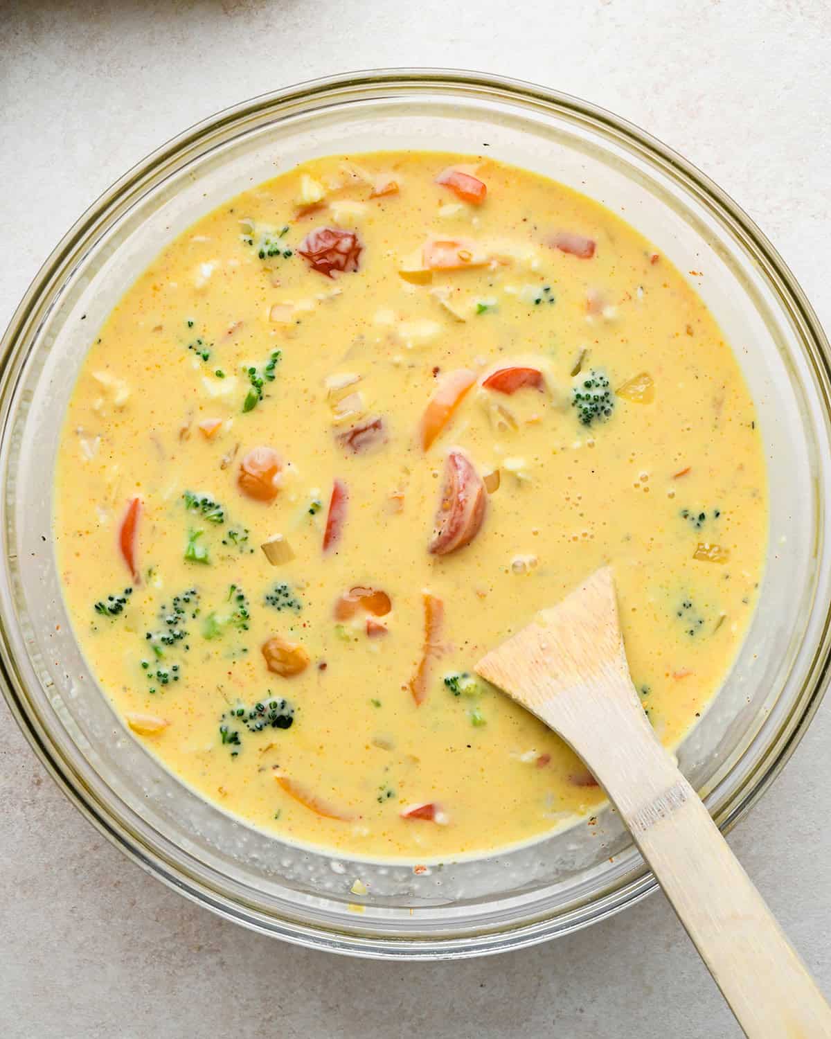 vegetable quiche filling in a bowl with a wooden spoon