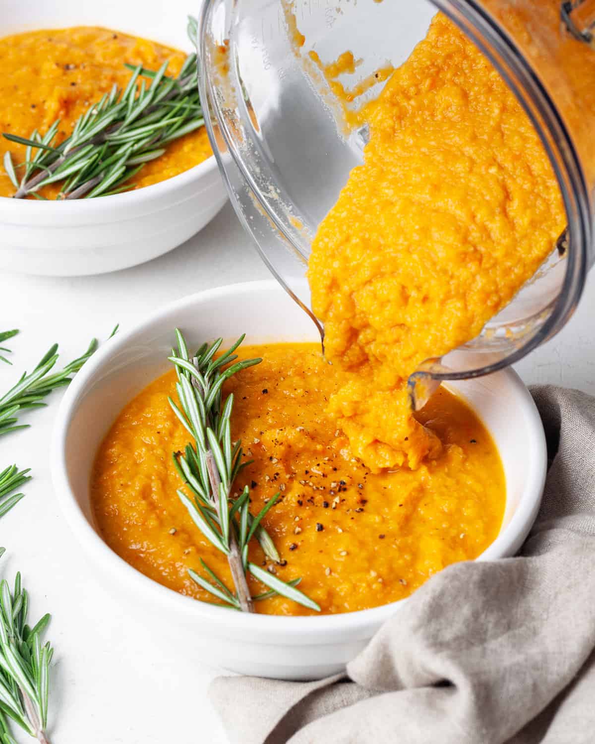 Roasted Vegetable Soup being poured from the blending container into a bowl