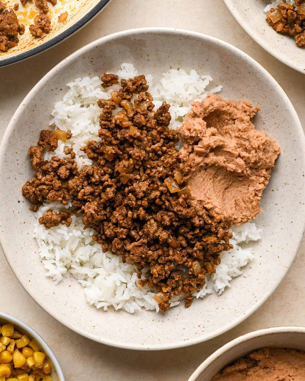 Assembling taco bowls - adding ground beef and beans