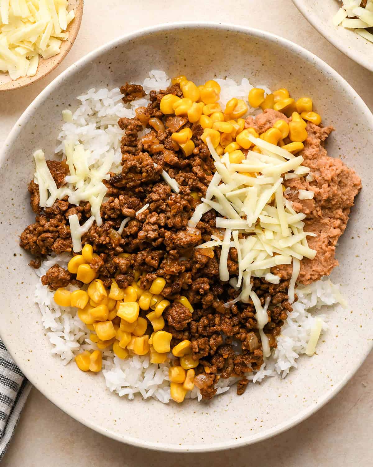 Assembling taco bowls - adding corn and cheese