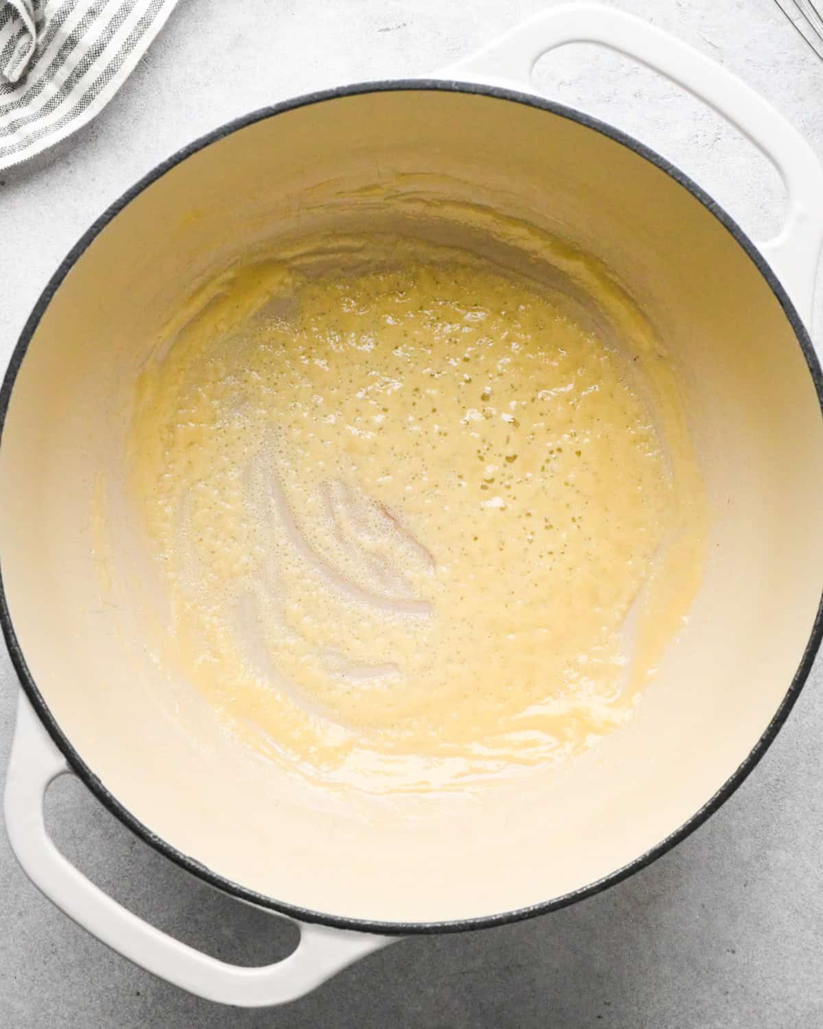 flour and melted butter cooking in a white pot making a roux to thicken this homemade tomato soup recipe