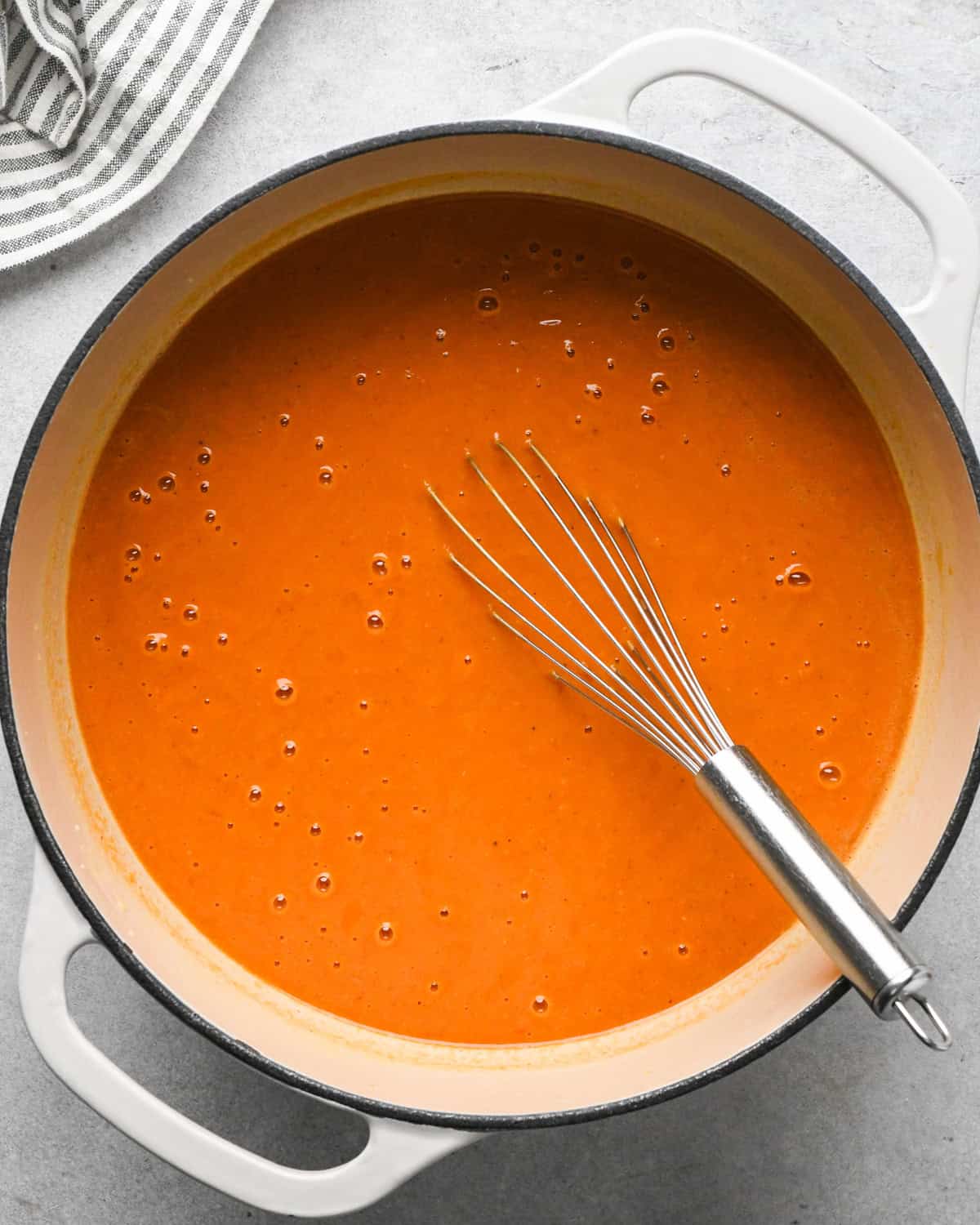 tomato soup in a pot with a wire whisk inside after mixing making tomato soup