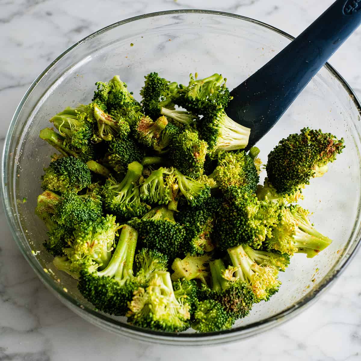 This is the best oven-roasted broccoli recipe! This easy roasted broccoli is made with 6 ingredients in 15 minutes! It's crispy, tender and perfectly seasoned! Baked broccoli is a healthy side dish that pairs well with everything! #broccoli #broccolirecipes #healthysidedish #sidedish #roastedbroccoli #joyfoodsunshine photo showing how to roast broccoli - stirring broccoli in a bowl