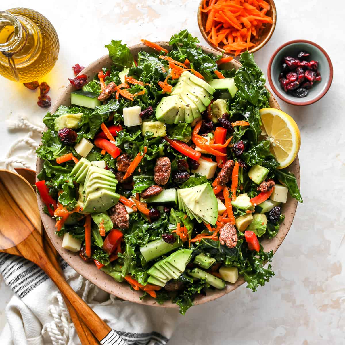 This kale salad recipe is loaded with colorful vegetables, sweet cranberries, crunchy pecans, creamy cheddar cheese and the best homemade dressing ever! It’s a hearty salad that holds up well and will impress even kale skeptics. overhead photo of Kale Salad in a bowl