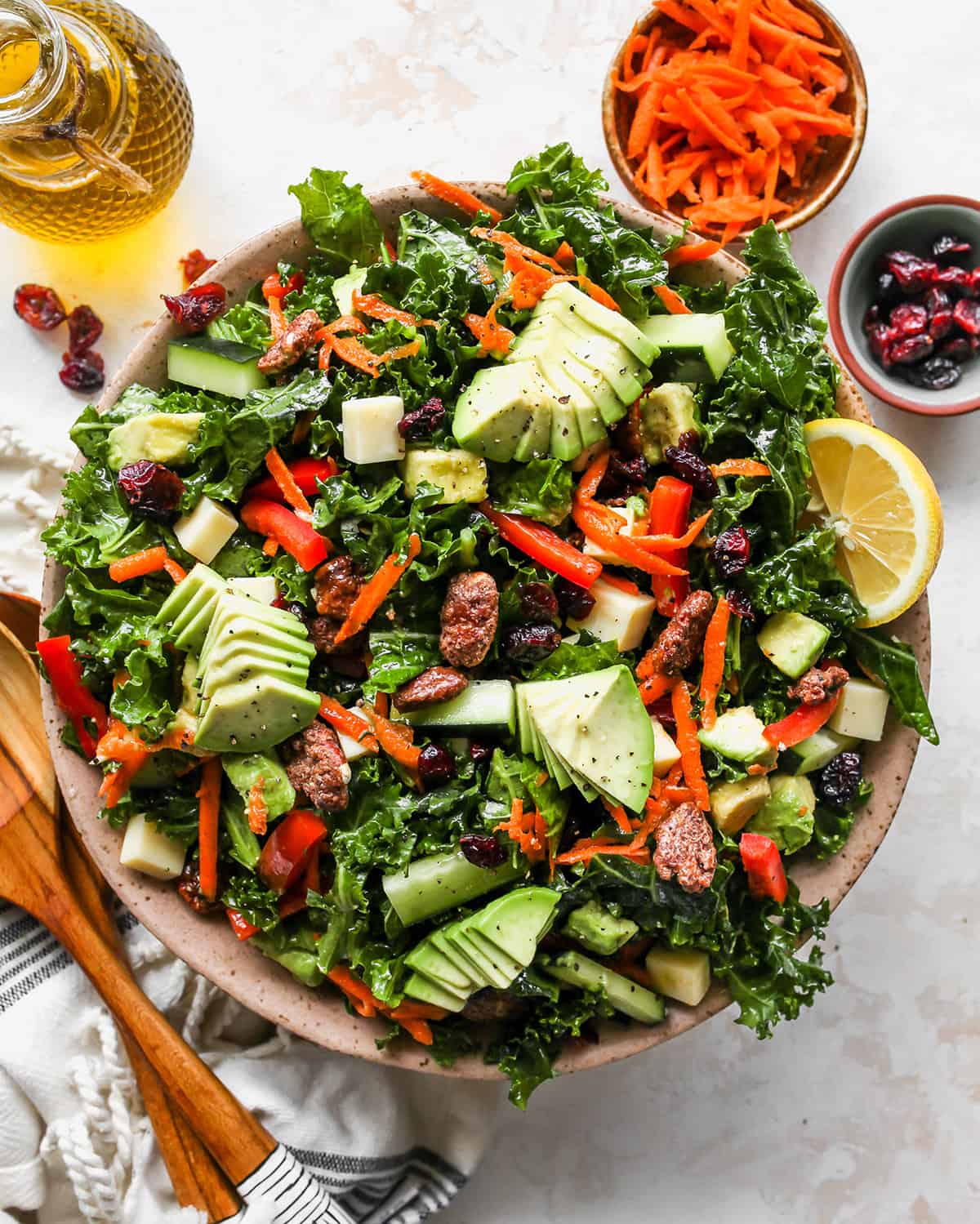 This kale salad recipe is loaded with colorful vegetables, sweet cranberries, crunchy pecans, creamy cheddar cheese and the best homemade dressing ever! It’s a hearty salad that holds up well and will impress even kale skeptics. overhead photo of Kale Salad in a bowl