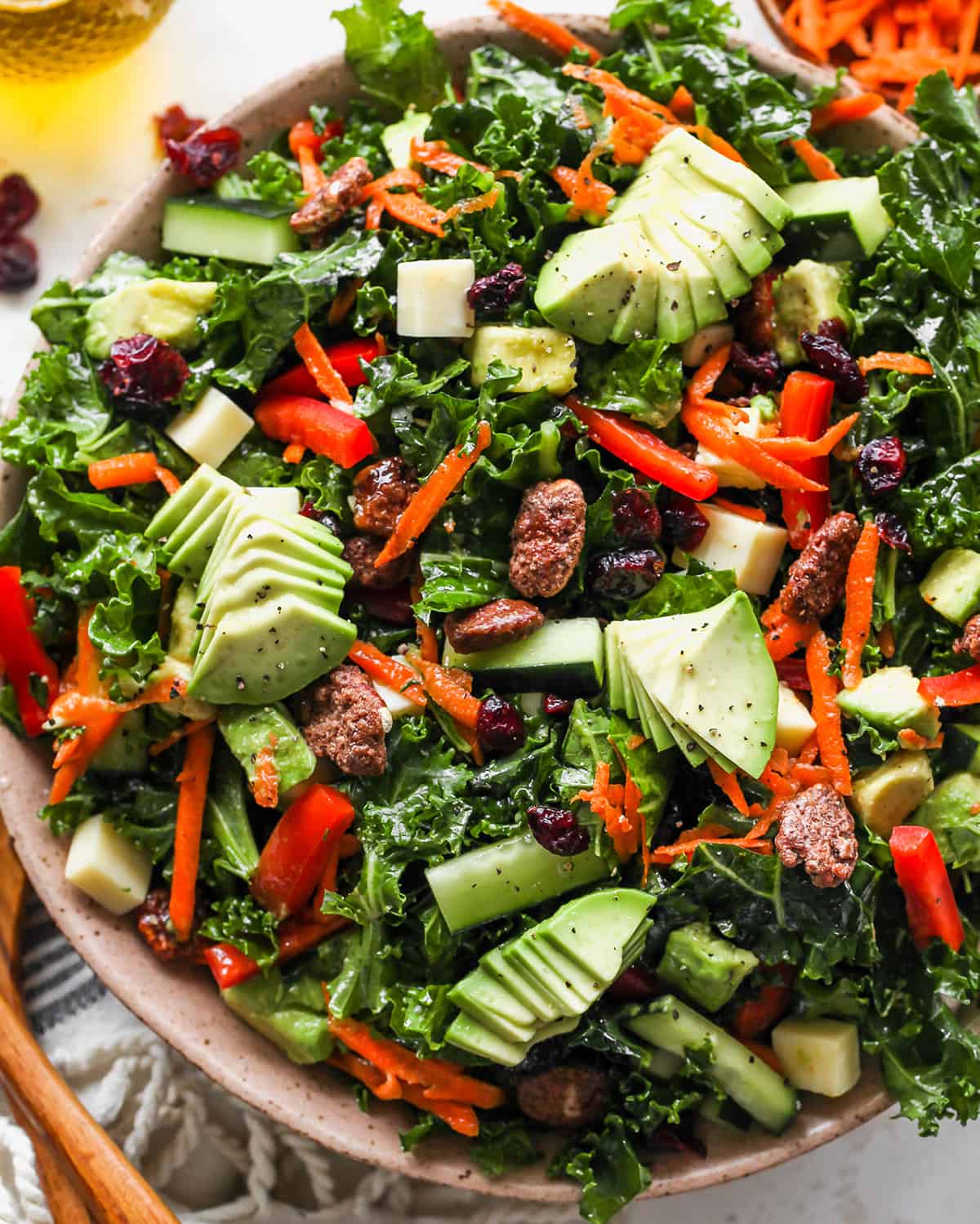 This kale salad recipe is loaded with colorful vegetables, sweet cranberries, crunchy pecans, creamy cheddar cheese and the best homemade dressing ever! It’s a hearty salad that holds up well and will impress even kale skeptics. up close overhead photo of Kale Salad Recipe