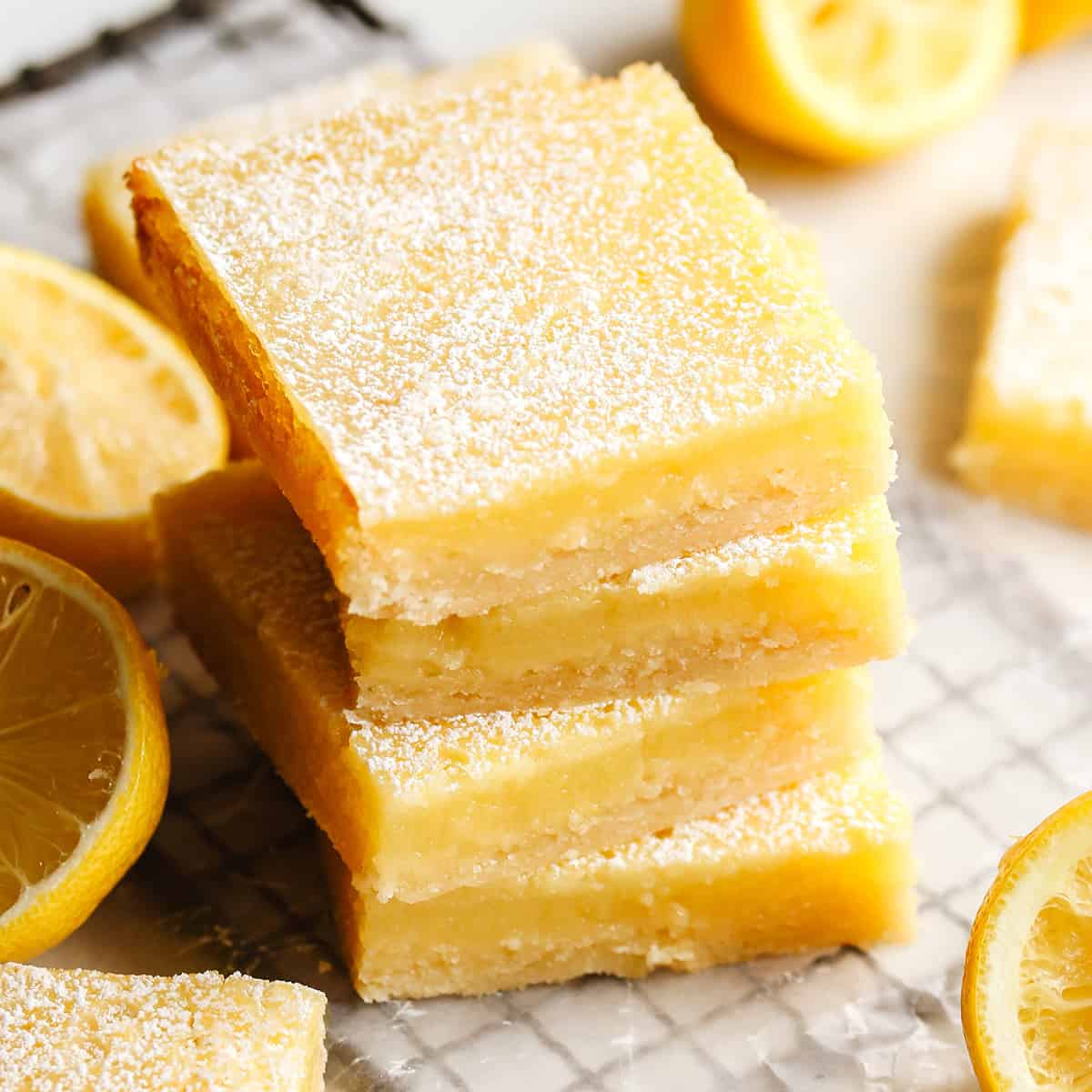 The best lemon bars! A smooth & sweet lemon filling sits on top of a buttery shortbread crust for the most delicious lemon squares recipe. Plus these easy lemon bars are simple to make with only 8 ingredients! stack of 4 lemon bars