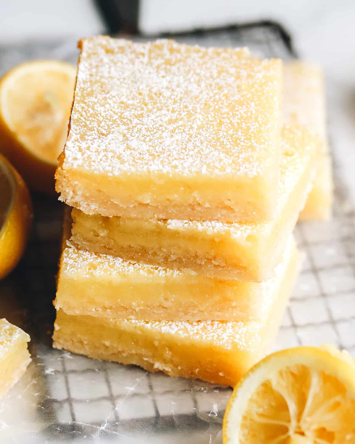 The best lemon bars! A smooth & sweet lemon filling sits on top of a buttery shortbread crust for the most delicious lemon squares recipe. Plus these easy lemon bars are simple to make with only 8 ingredients! front view of a stack of 4 lemon bars