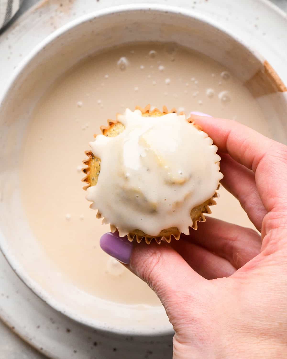 a Lemon Poppy Seed Muffin after being dipped into a bowl of glaze