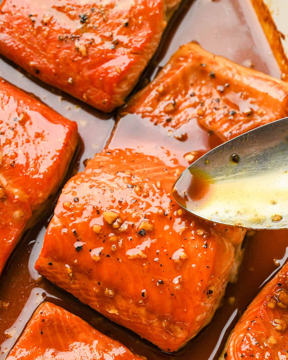 a spoon pouring glaze over maple glazed salmon