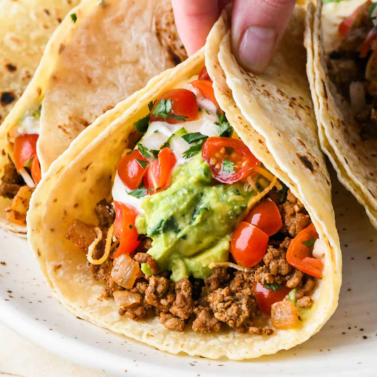 a hand holding a ground beef taco