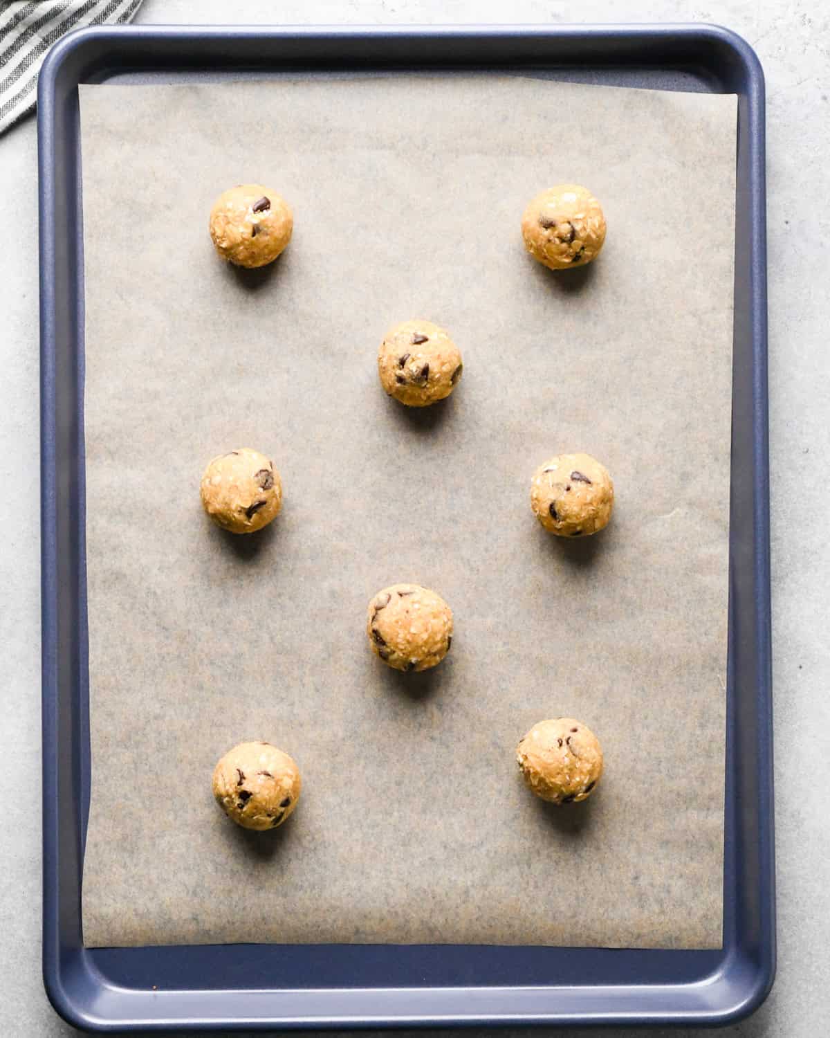 8 oatmeal chocolate chip cookies on a baking sheet lined with parchment paper before baking