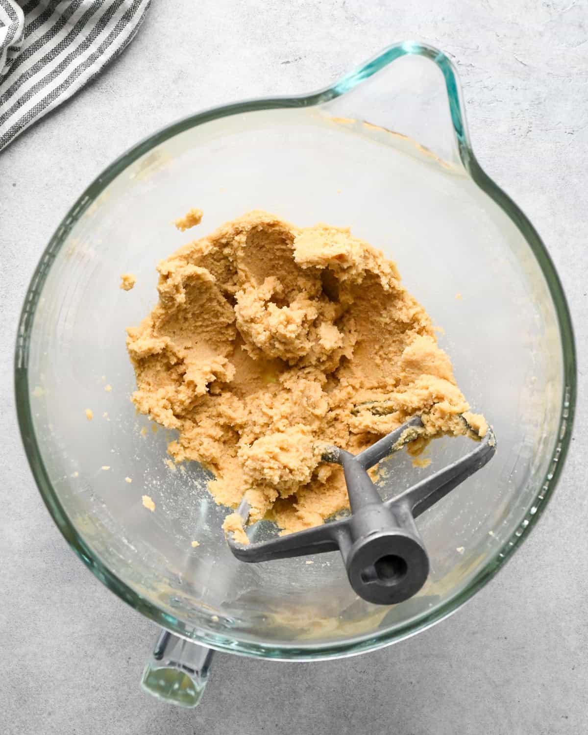 making chocolate chip oatmeal cookies - beaten butter and sugar mixture in a glass mixing bowl with the paddle attachement