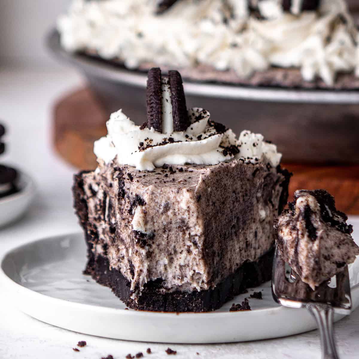 front view of a slice of Oreo pie on a plate with a fork holding a bite taken out of it