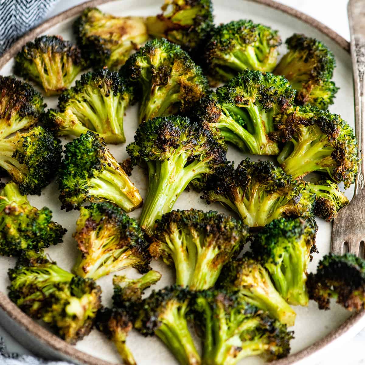 This is the best oven-roasted broccoli recipe! This easy roasted broccoli is made with 6 ingredients in 15 minutes! It's crispy, tender and perfectly seasoned! Baked broccoli is a healthy side dish that pairs well with everything! #broccoli #broccolirecipes #healthysidedish #sidedish #roastedbroccoli #joyfoodsunshine overhead view of oven roasted broccoli on a plate