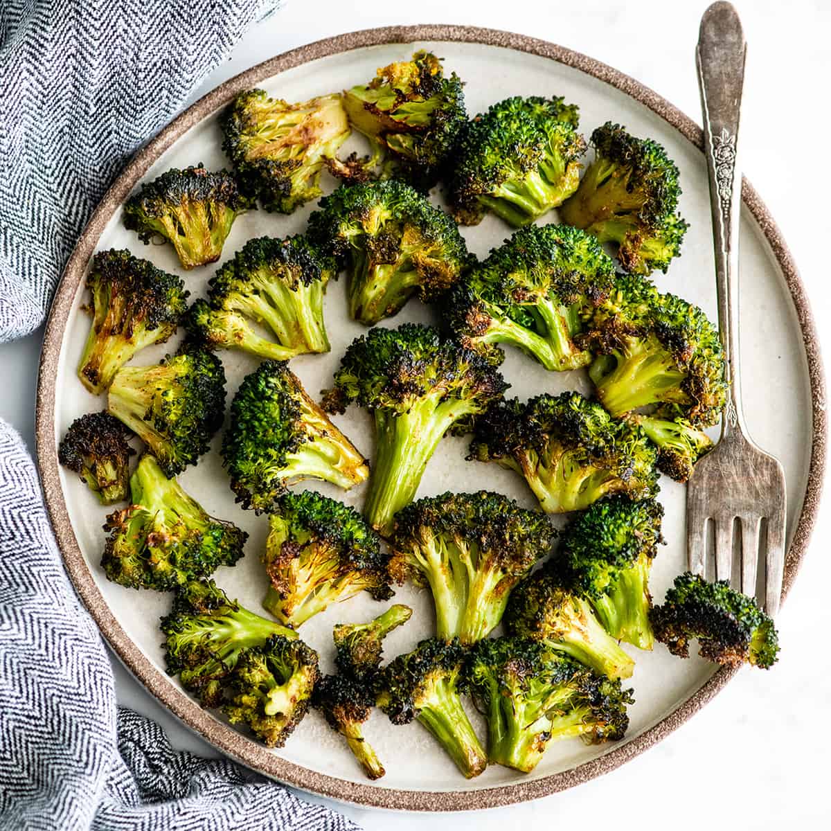 This is the best oven-roasted broccoli recipe! This easy roasted broccoli is made with 6 ingredients in 15 minutes! It's crispy, tender and perfectly seasoned! Baked broccoli is a healthy side dish that pairs well with everything! #broccoli #broccolirecipes #healthysidedish #sidedish #roastedbroccoli #joyfoodsunshine overhead view of roasted broccoli on a plate