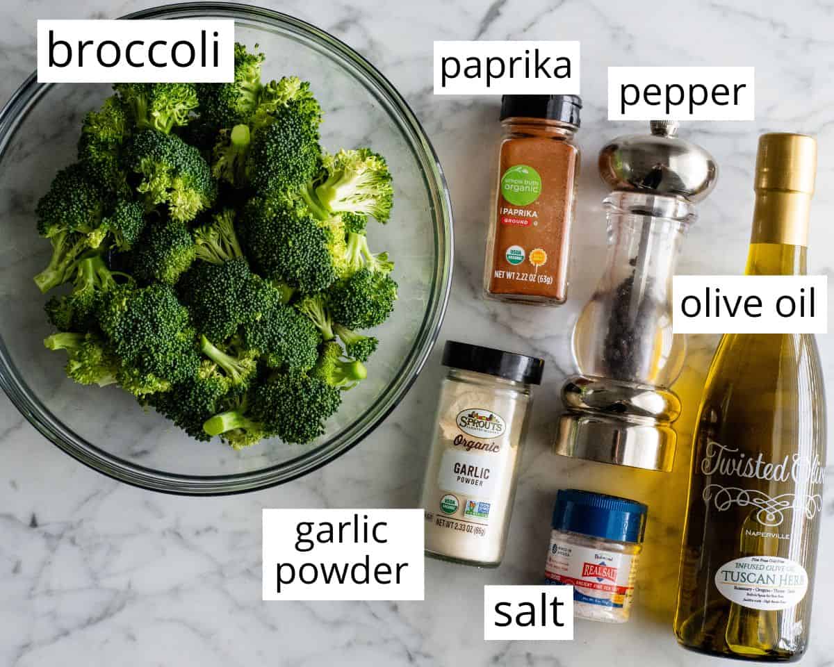 This is the best oven-roasted broccoli recipe! This easy roasted broccoli is made with 6 ingredients in 15 minutes! It's crispy, tender and perfectly seasoned! Baked broccoli is a healthy side dish that pairs well with everything! #broccoli #broccolirecipes #healthysidedish #sidedish #roastedbroccoli #joyfoodsunshine overhead view of the labeled ingredients in this roasted broccoli recipe