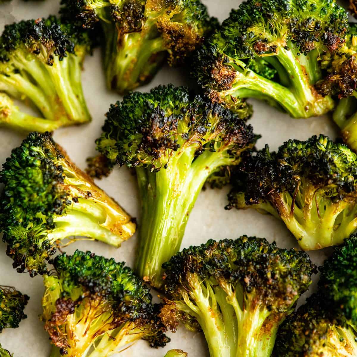 This is the best oven-roasted broccoli recipe! This easy roasted broccoli is made with 6 ingredients in 15 minutes! It's crispy, tender and perfectly seasoned! Baked broccoli is a healthy side dish that pairs well with everything! #broccoli #broccolirecipes #healthysidedish #sidedish #roastedbroccoli #joyfoodsunshine up close photo of 9 pieces of oven roasted broccoli on a plate