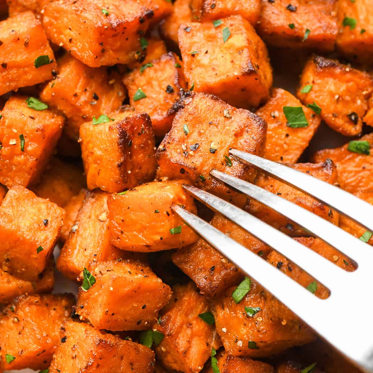 a fork taking a bite of Oven Roasted Sweet Potatoes