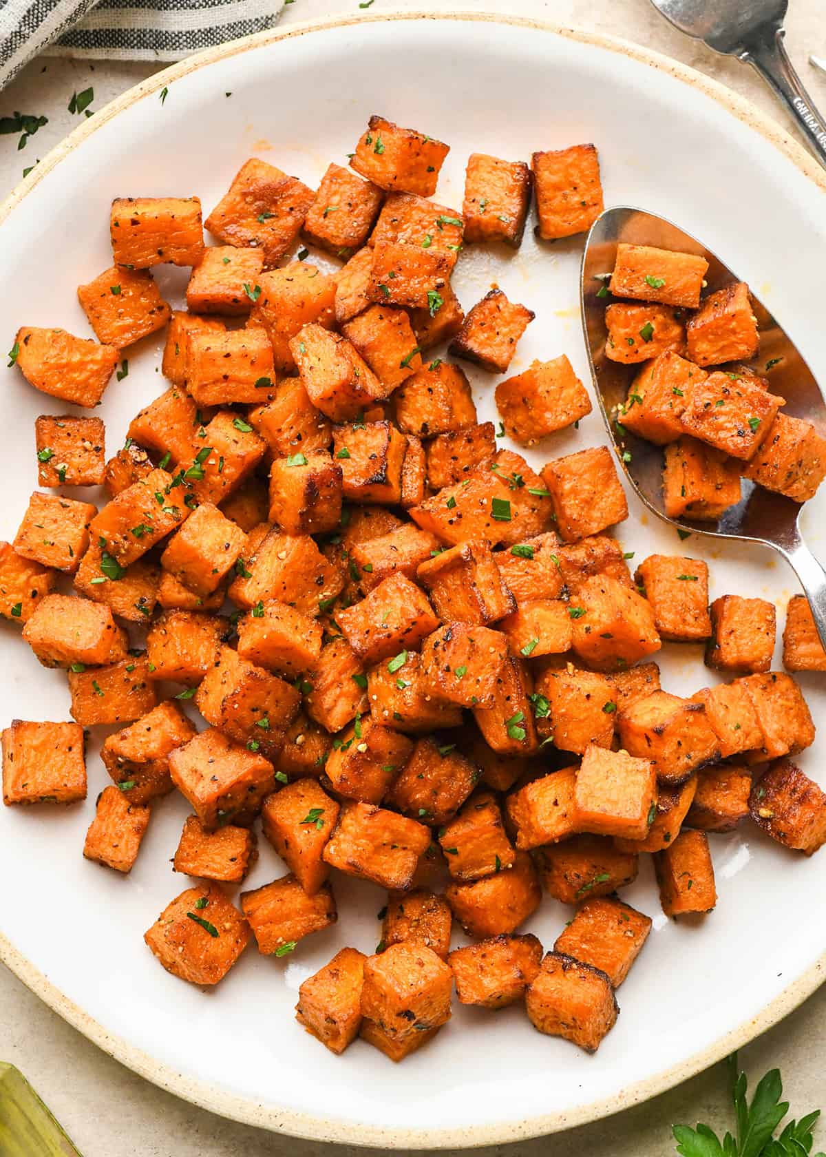 Oven Roasted Sweet Potatoes on a serving plate with a spoon