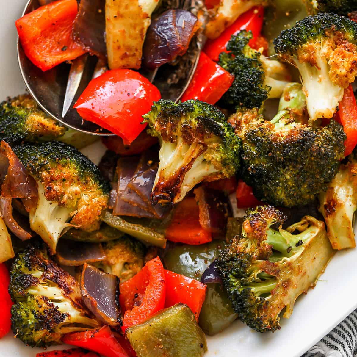 The best oven roasted vegetables recipe! Your favorite veggies are tossed in olive oil and a delicious spice mixture and are roasted until they are perfectly tender and slightly crispy. Baked vegetables are easy to make and a great way to meal prep vegetables for the week. up close, overhead view of Oven Roasted Vegetables on a serving platter