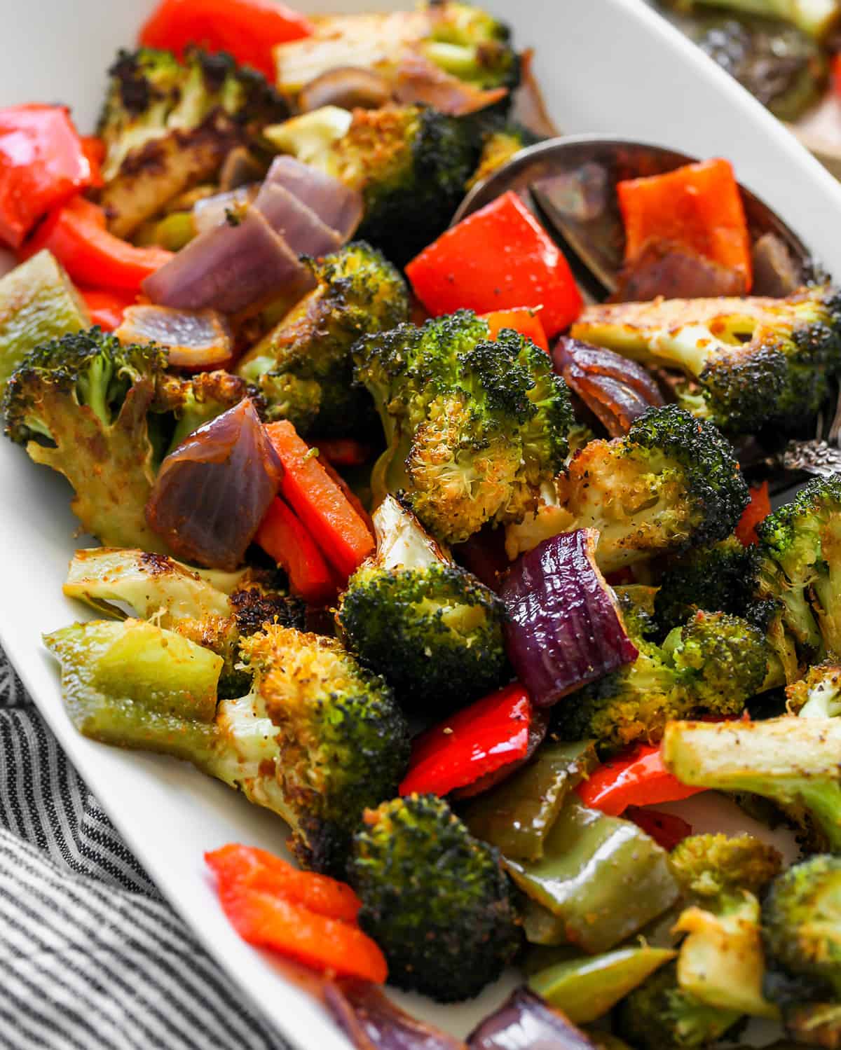 The best oven roasted vegetables recipe! Your favorite veggies are tossed in olive oil and a delicious spice mixture and are roasted until they are perfectly tender and slightly crispy. Baked vegetables are easy to make and a great way to meal prep vegetables for the week. up close overhead view of Roasted Vegetables on a plate