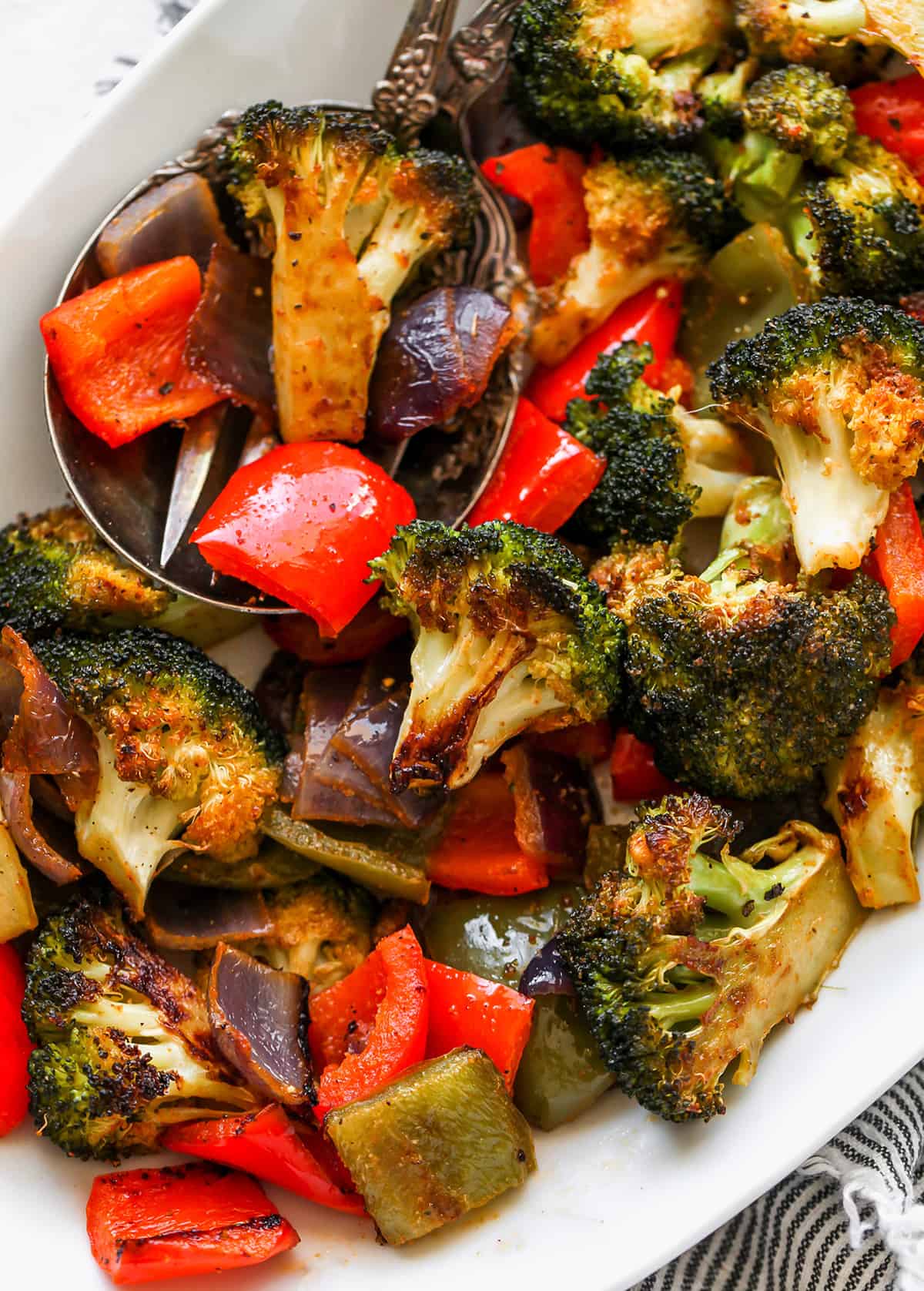 The best oven roasted vegetables recipe! Your favorite veggies are tossed in olive oil and a delicious spice mixture and are roasted until they are perfectly tender and slightly crispy. Baked vegetables are easy to make and a great way to meal prep vegetables for the week. overhead view of Oven Roasted Vegetables on a serving platter