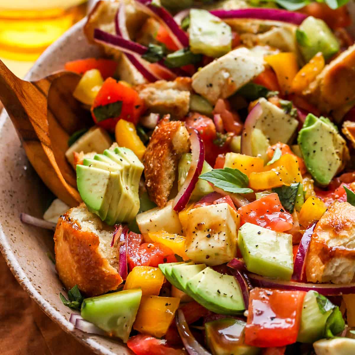 a salad spoon scooping a portion of panzanella salad out of a bowl