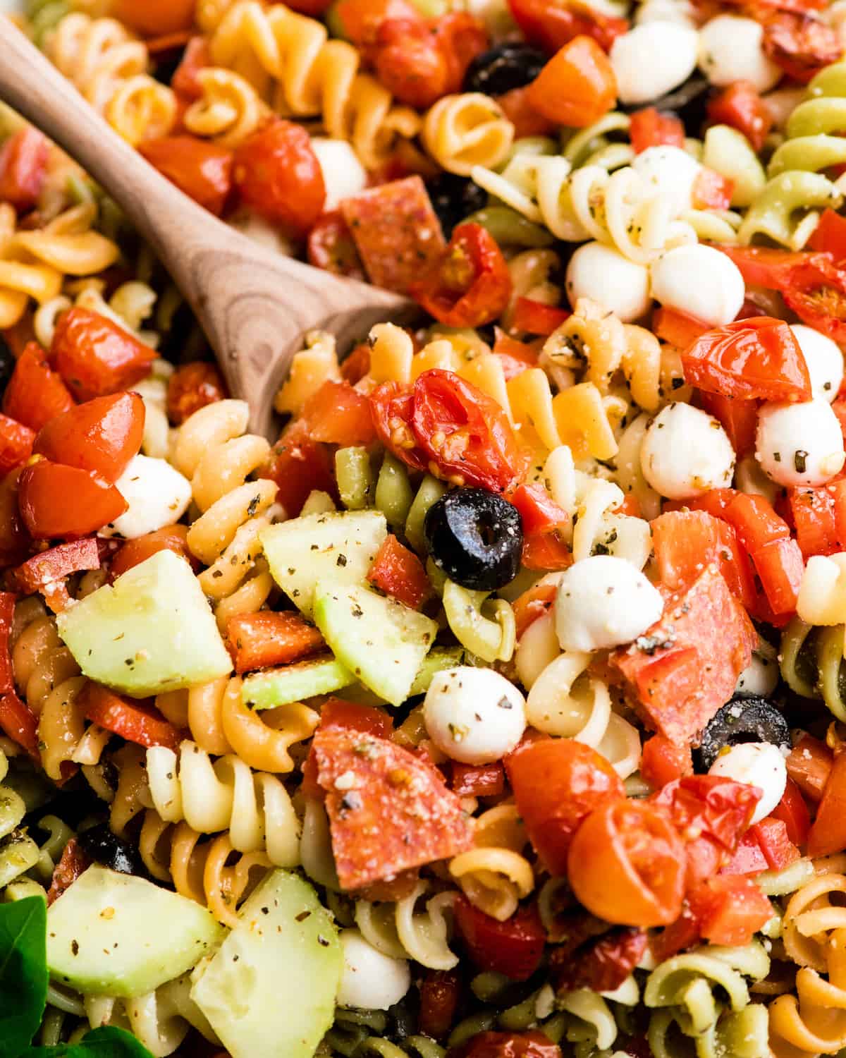 This Best Pasta Salad Recipe is made with Homemade Dressing & Roasted Tomatoes! It is the perfect healthy & flavorful make-ahead BBQ side dish full of fresh veggies, pepperoni and fresh mozzarella cheese! #pastasalad #bbq #sidedish #bestpastasalad #pastasaladrecipe #recipe #healthyrecipe #easypastasalad #homemadedressing overhead view of the best pasta salad recipe in a large white serving bowl