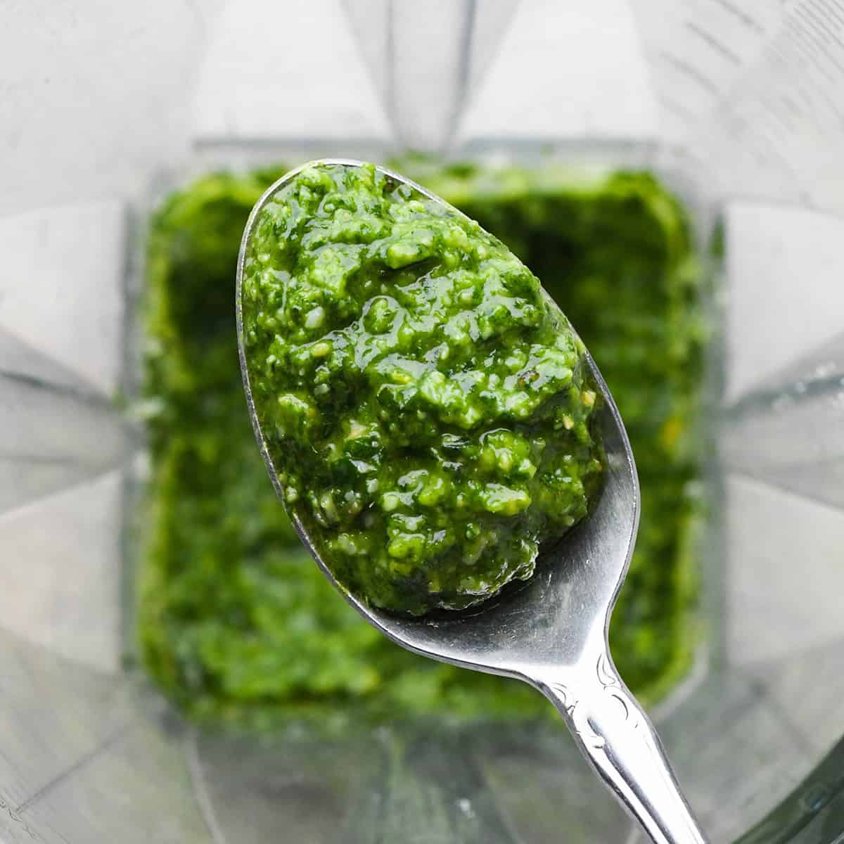 pesto pasta on a spoon over the blending container to show consistency