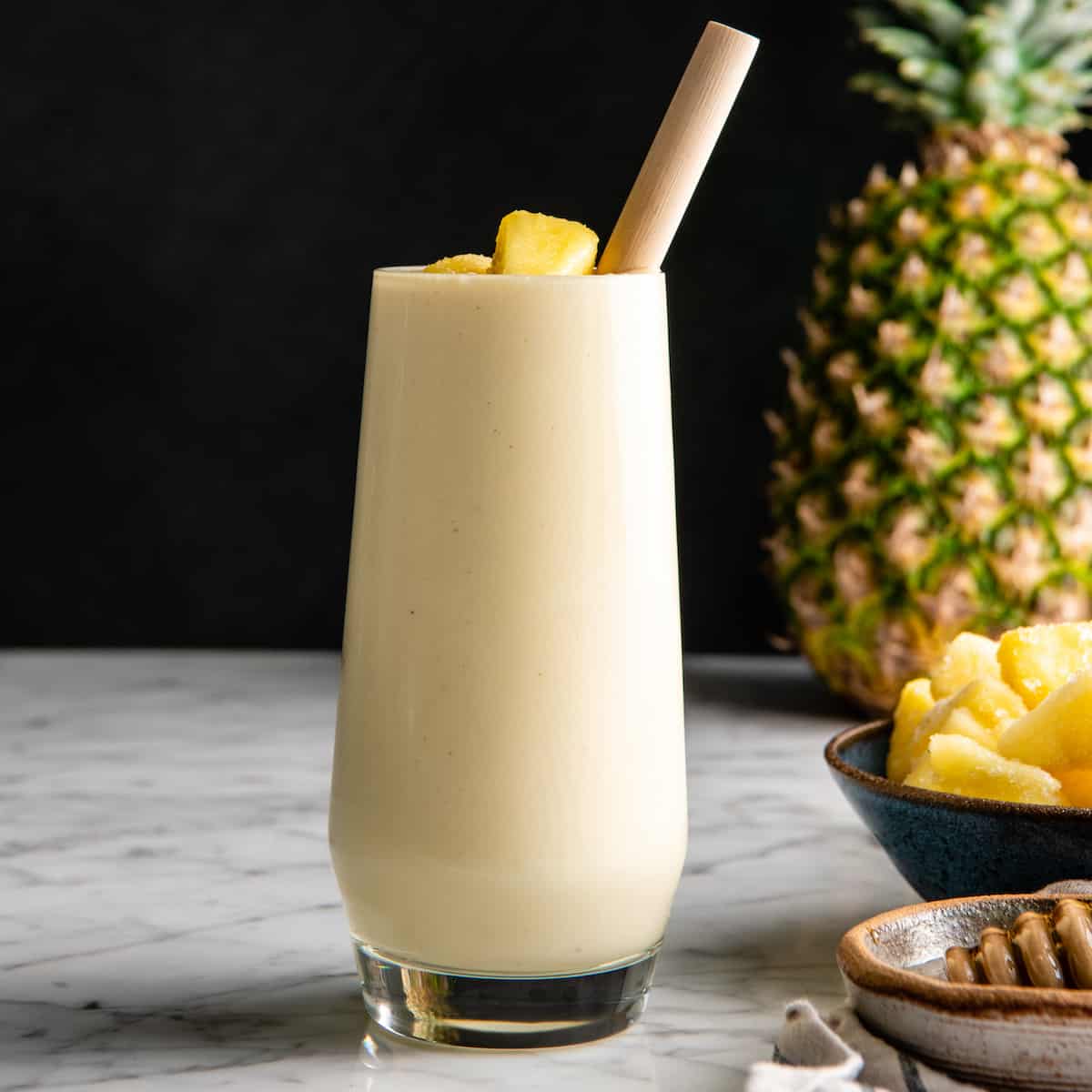 This healthy Pineapple Smoothie recipe is easy to make with only 5 ingredients in 5 minutes! One sip of this pineapple banana smoothie will make you feel like you're on a tropical island, it's like a beach vacation in a glass! Plus it's dairy-free! #pineapple #smoothie #pineapplesmoothie #banana #joyfoodsunshine #smoothierecipe front view of a pineapple smoothie in a glass