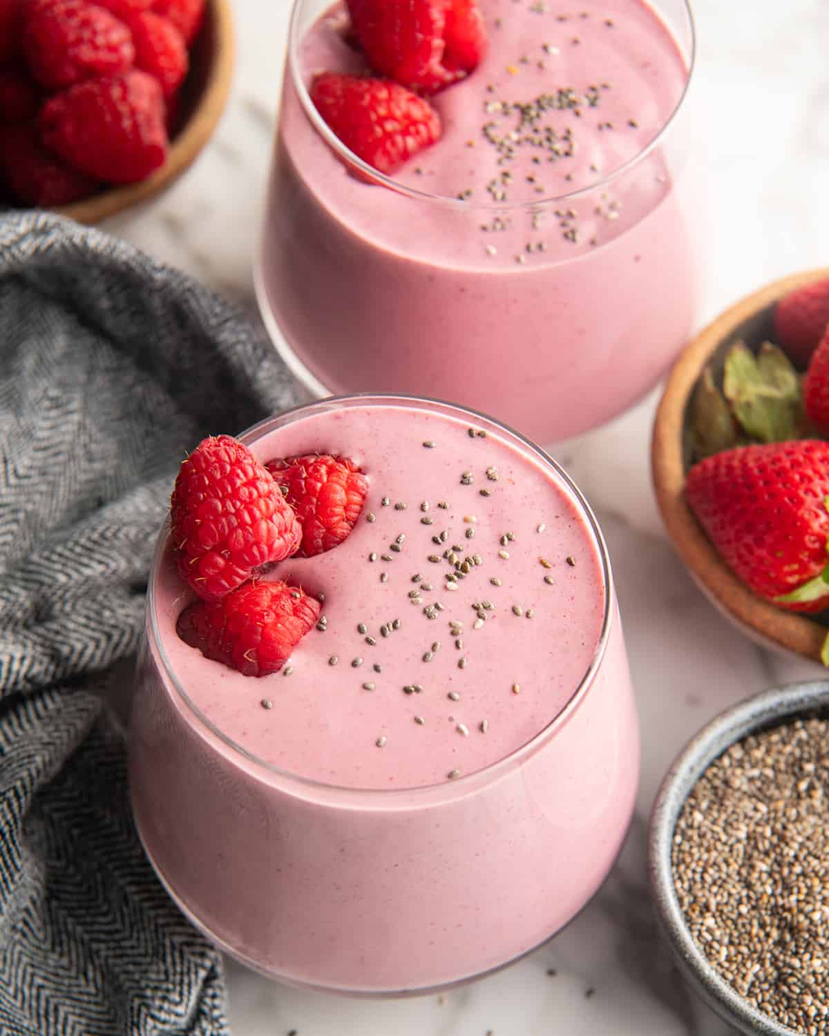 two glasses of Protein Smoothie with raspberries and chia seeds on top