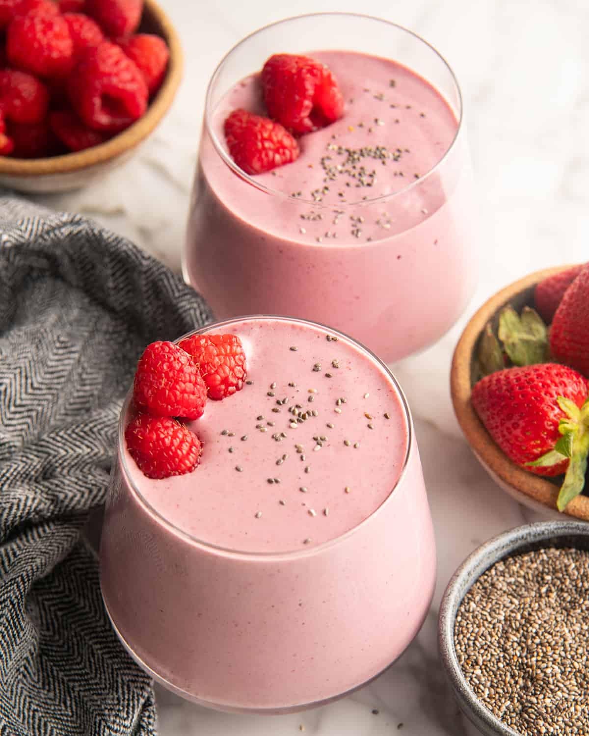 two glasses of Protein Smoothie Recipe with chia seeds and raspberries on top