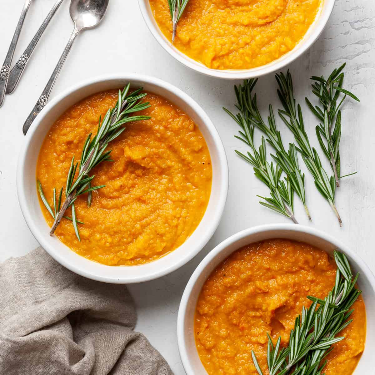 3 bowls of Roasted Vegetable Soup garnished with rosemary