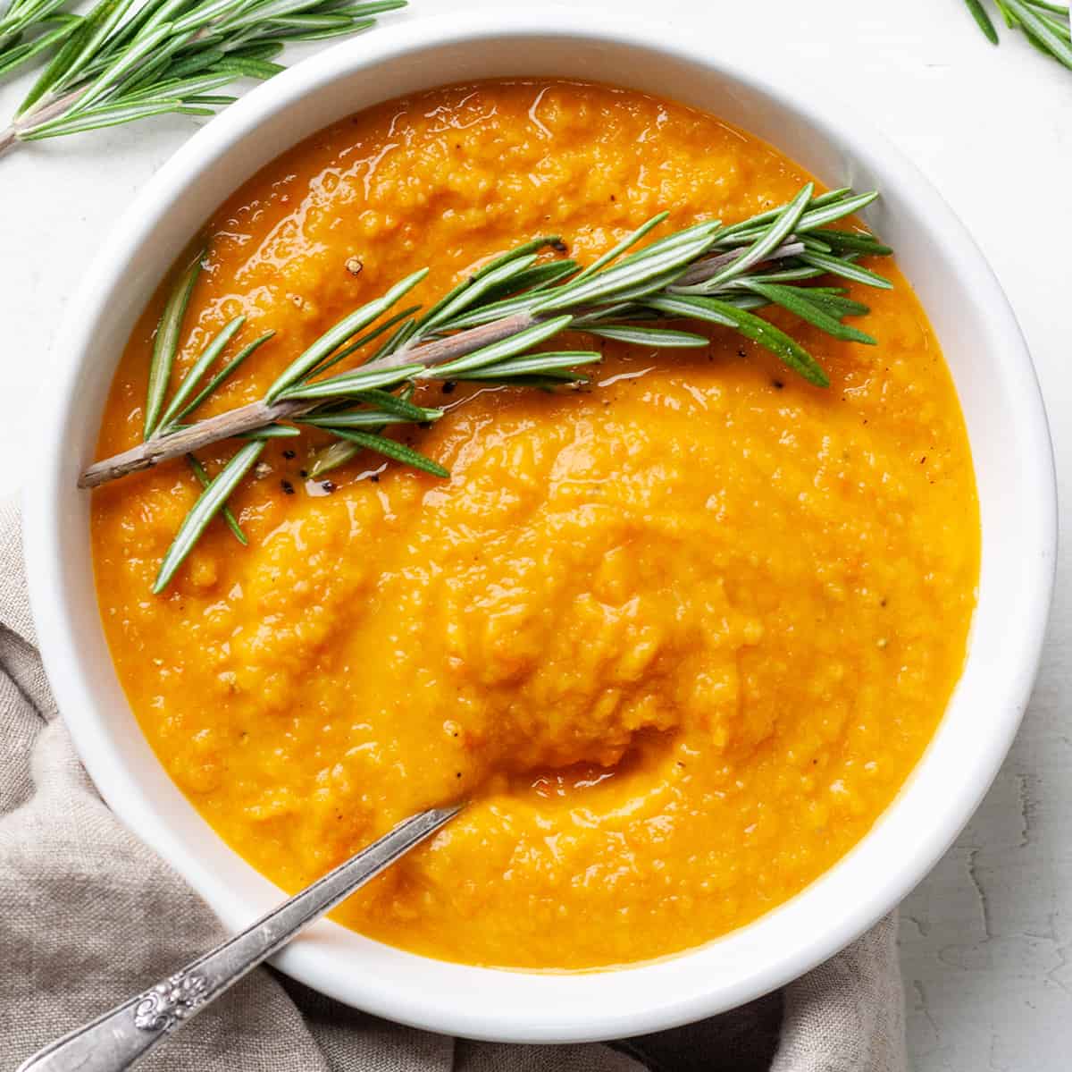 a bowl of Roasted Vegetable Soup with fresh rosemary and a spoon